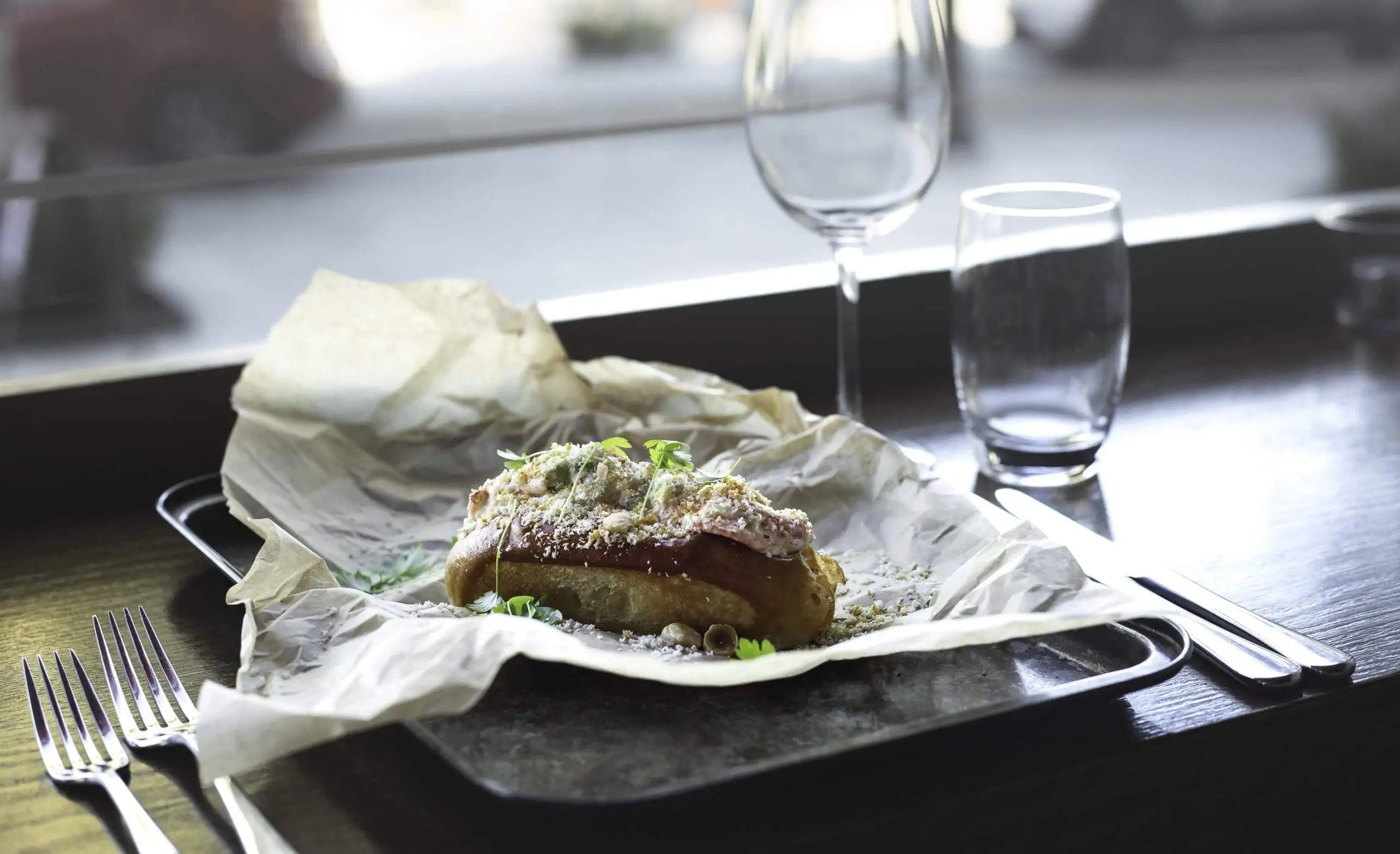 A filled lobster roll sits half unwrapped in paper on a countertop facing the window at Lobstar, a restaurant in Dublin