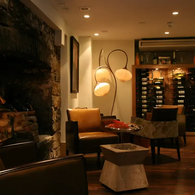 The interior of Pearl Brasserie with wine racks, soft armchairs and warm lighting from unique lamps and a fireplace.