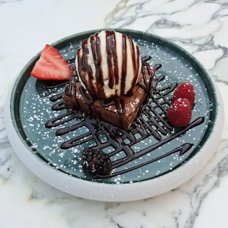 A slice of brownie topped with a scoop of vanilla ice cream and chocolate sauce served at Sandyford House, one of the best pubs in Dublin.