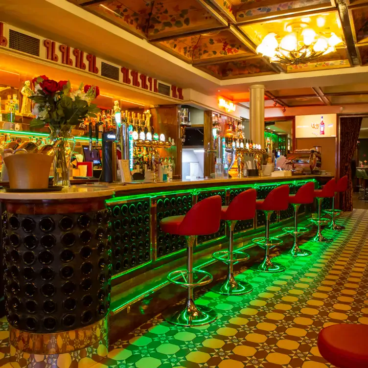 A long bar with green lighting underneath at Davy Byrnes, one of the best pubs in Dublin.