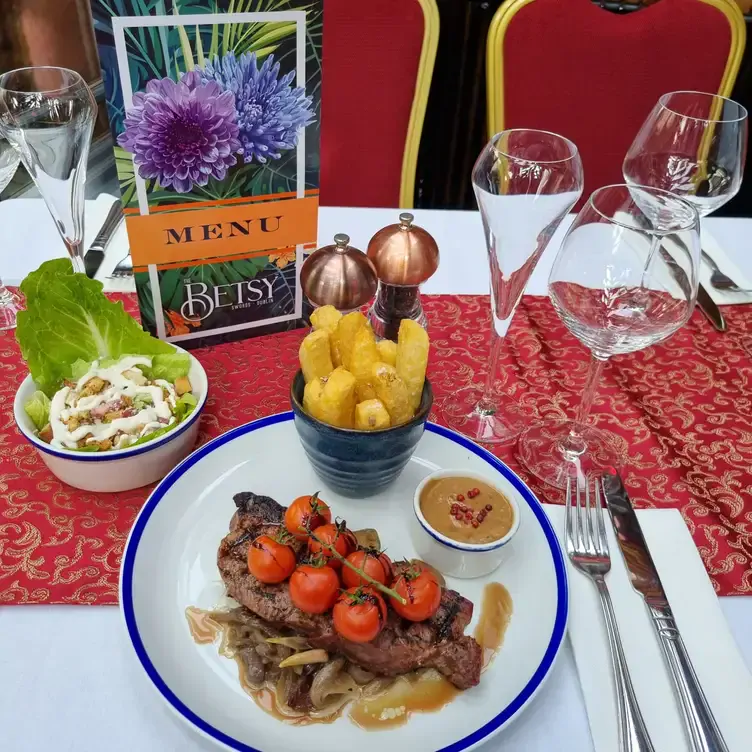 A plate of steak, topped with cherry tomatoes served alongside thick-cut chips and a salad at The Betsy Swords.