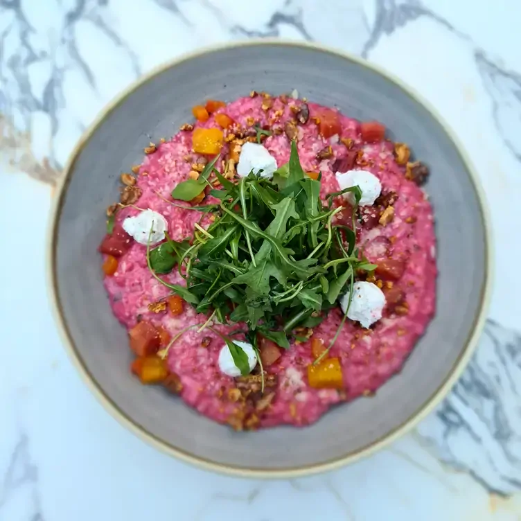 A bowl of beetroot risotto topped with rocket leaves and cheese served at Sandyford House.