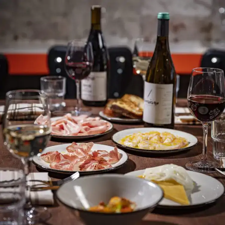 A spread of shareable plates featuring ham and cheese alongside wine bottles at Amy Austin, one of the best local restaurants in Dublin.