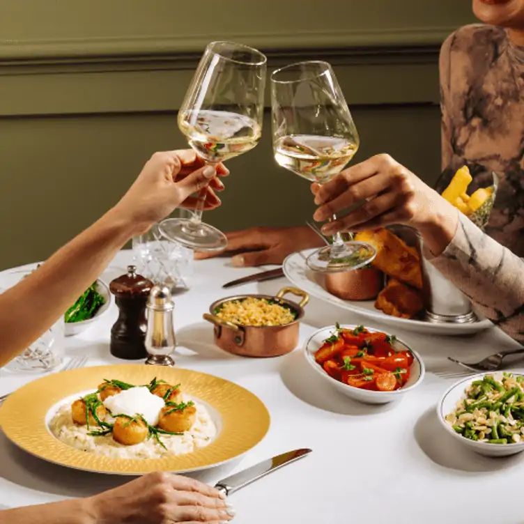 Diners drinking white wine and eating scallops at The Ivy Dawson, one of the best lunch restaurants in Dublin.