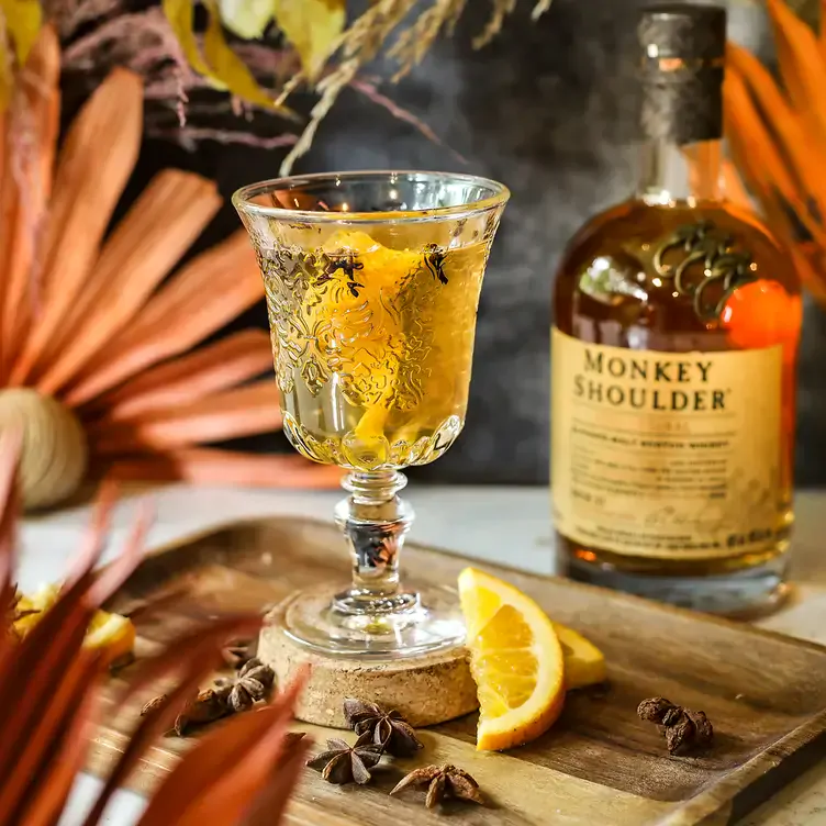 A cocktail in a decorative glass and a whisky bottle at FIRE Steakhouse & Bar, one of the best restaurants in Dublin city.