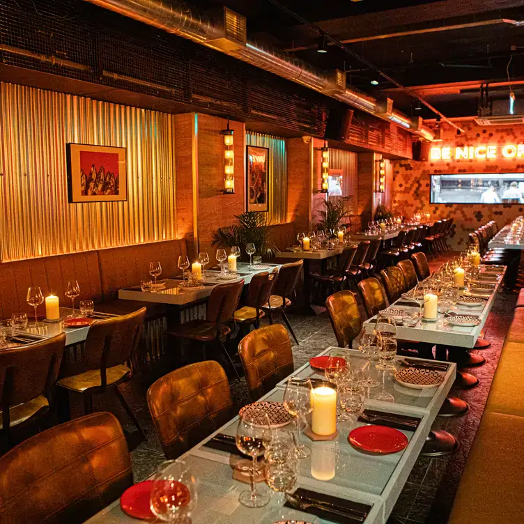 Dimli-lit interiors with long tables and a red neon sign at Krewe North, one of the best local restaurants in Dublin.