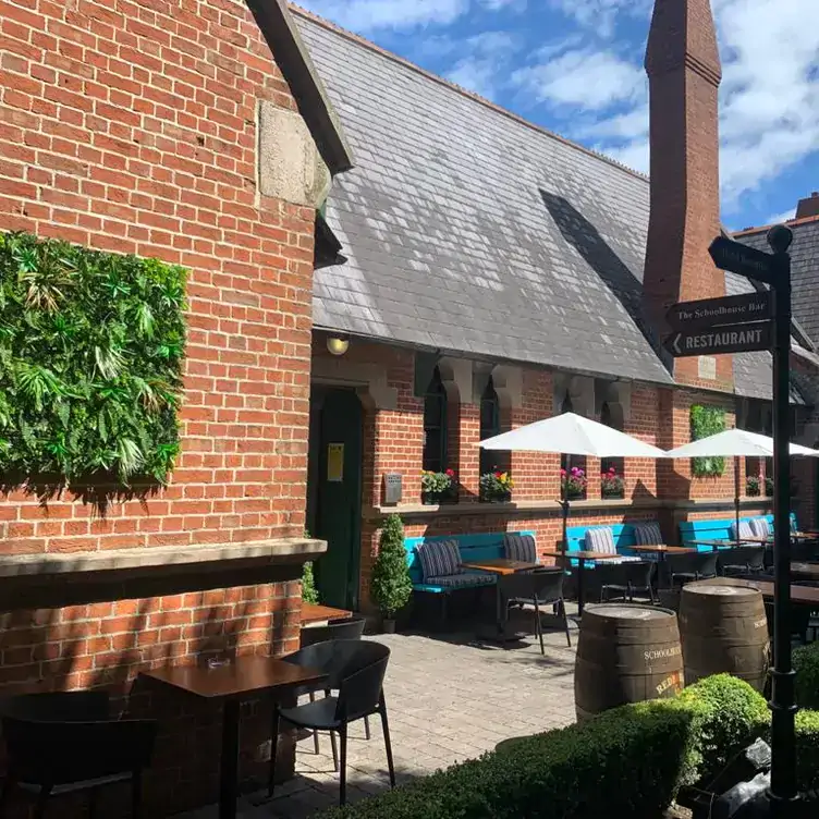 The outdoor dining area with blue benches and white beach umbrellas at The Schoolhouse Dublin, one of the best beer gardens in Dublin.