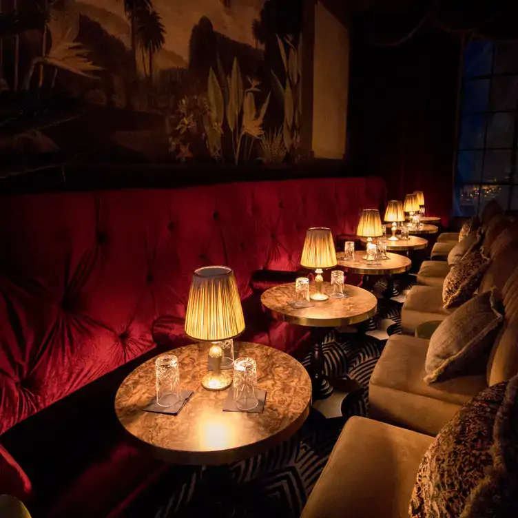 Warm and intimate seating with red velvet and gold fabrics and table lamps at Stella Cocktail Club, one of the best bars in Dublin.