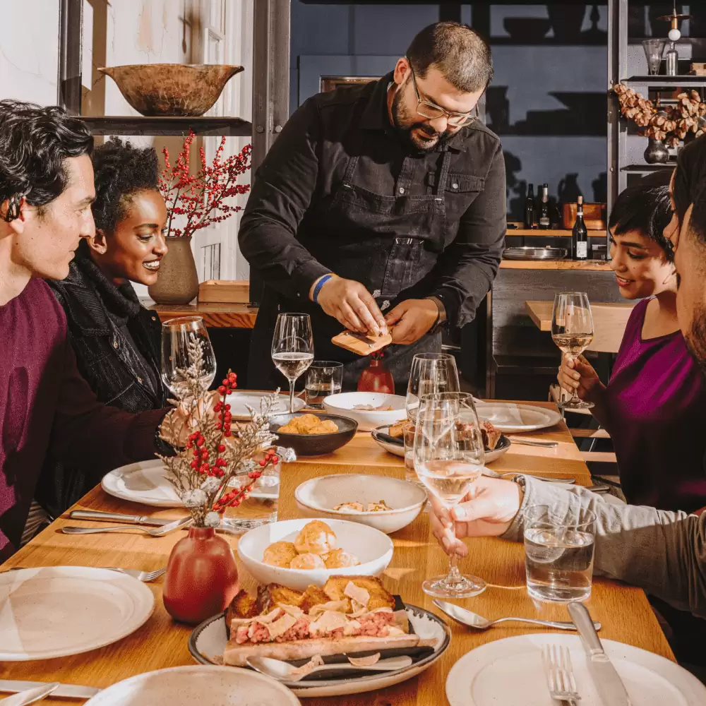 Diners sat at a table looking at waiter to grating truffle