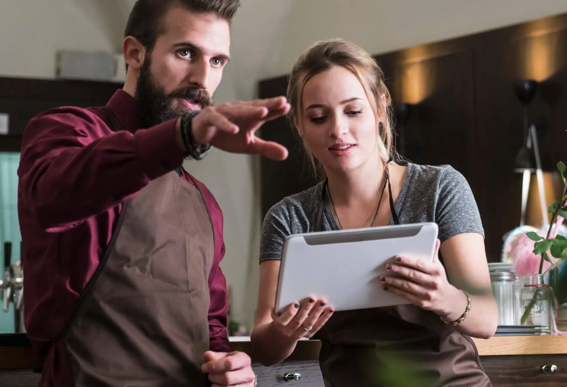 Two restaurant employees are looking at a tablet